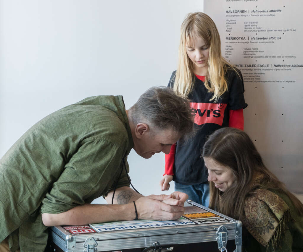 Two adults and a child are inspecting a box.