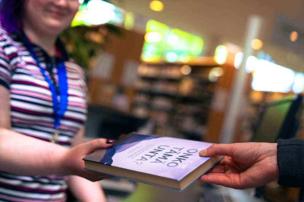 En kvinna håller fram en bok.