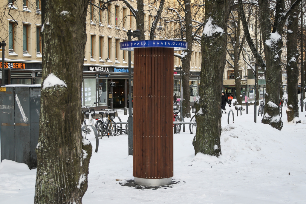 Kuvassa ruskea, pyöreä noin kaksimetrinen mainopyloni, jossa on Vaasa-logot.