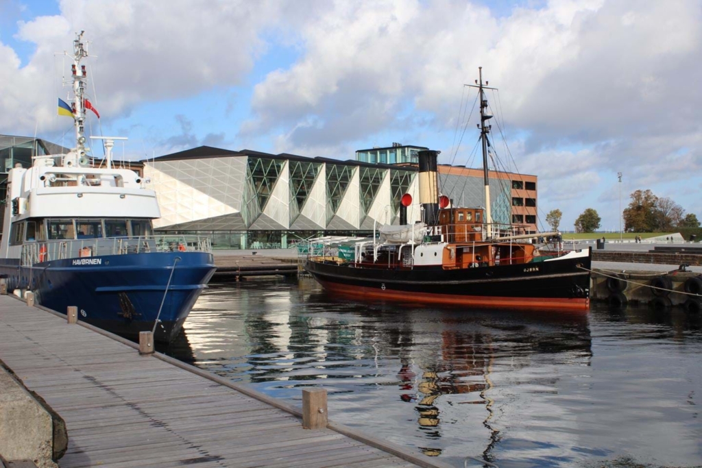 En hamn med två båtar och kulturcentret i bakgrunden.