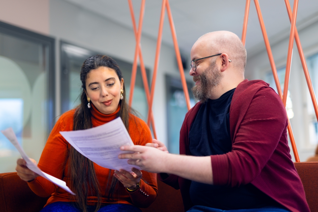 A woman and a man are looking at a paper togehter.