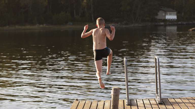 Pojken hoppar i vattnet