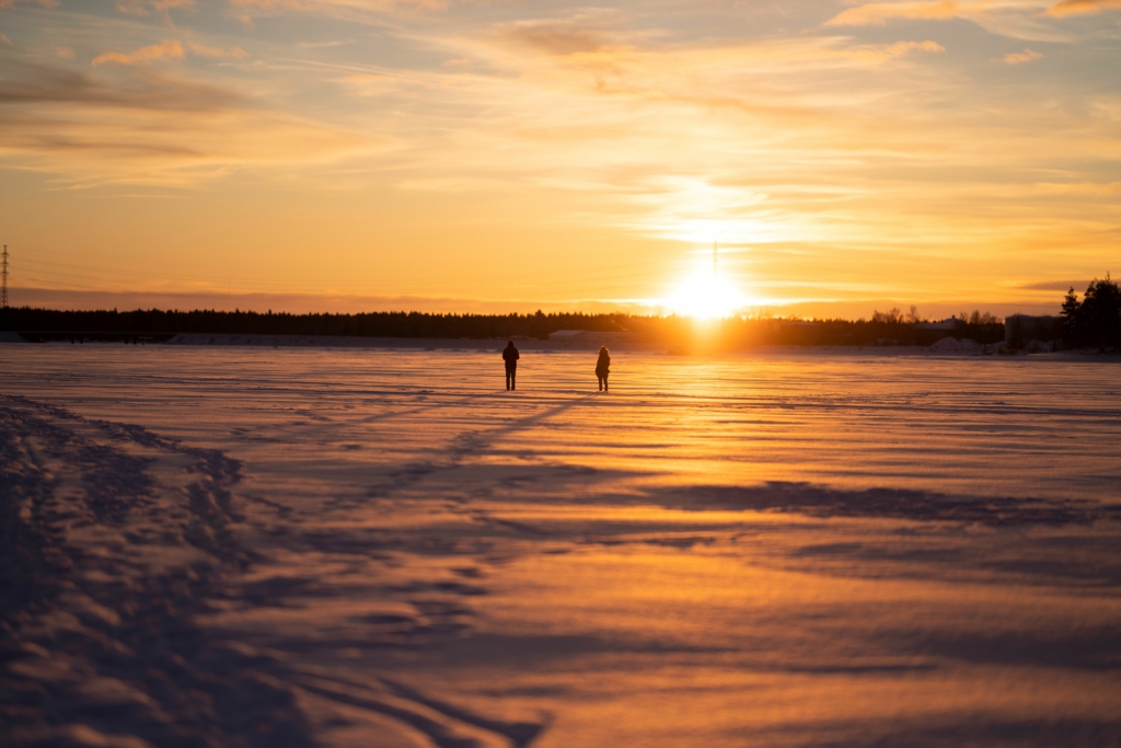 Two persons walking on the ice towards a glimmer of sunlight